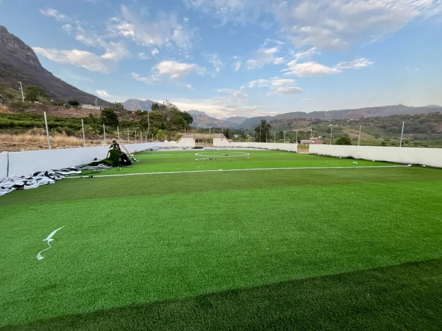 Metro de pasto sintético ya instalado: cancha lista con líneas de juego y vista a la montaña