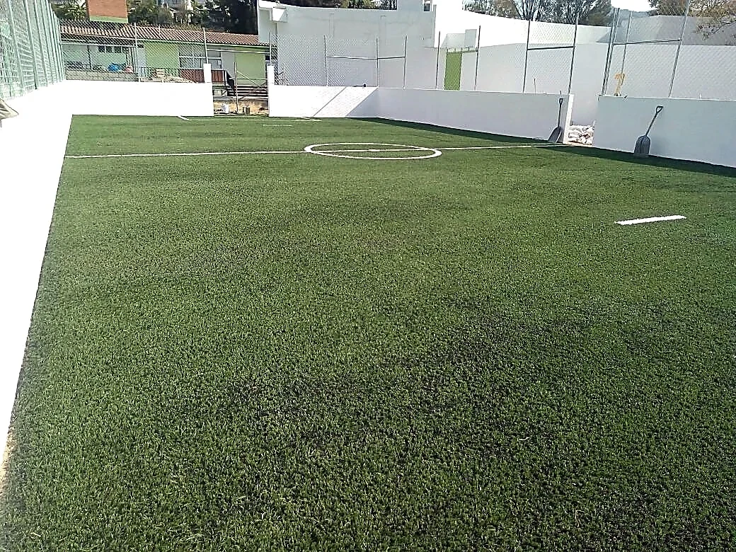 Cancha de fútbol 7 con pasto sintético en Esc. Primaria Benito Juárez, Zumpahuacan, Estado de México: la cancha desde la línea lateral
