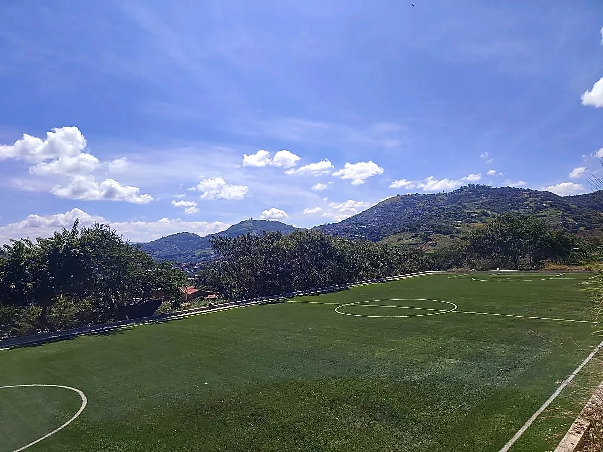 Cancha de fútbol 7 con pasto sintético en Escuela Primaria Bilingüe Emiliano Zapata, Temalacatzingo, Guerrero: líneas de juego insertadas en el mismo pasto