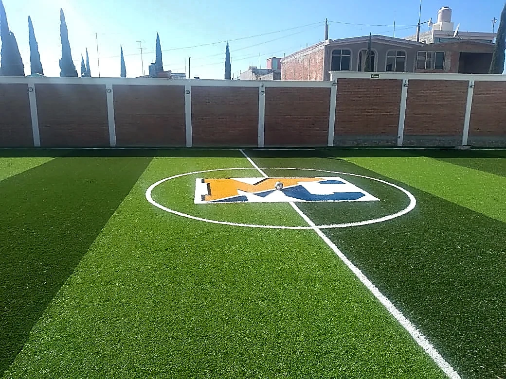Cancha de fútbol 5 con pasto sintético en Secundaria Marie Curie, Actopan, Hidalgo: líneas insertadas en el pasto sintético