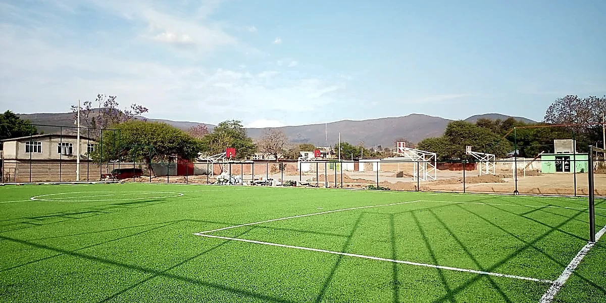 Cancha de fútbol 7 con pasto sintético en Unidad Deportiva Santa Maria Coyotepec, Oaxaca: la cancha desde la línea lateral