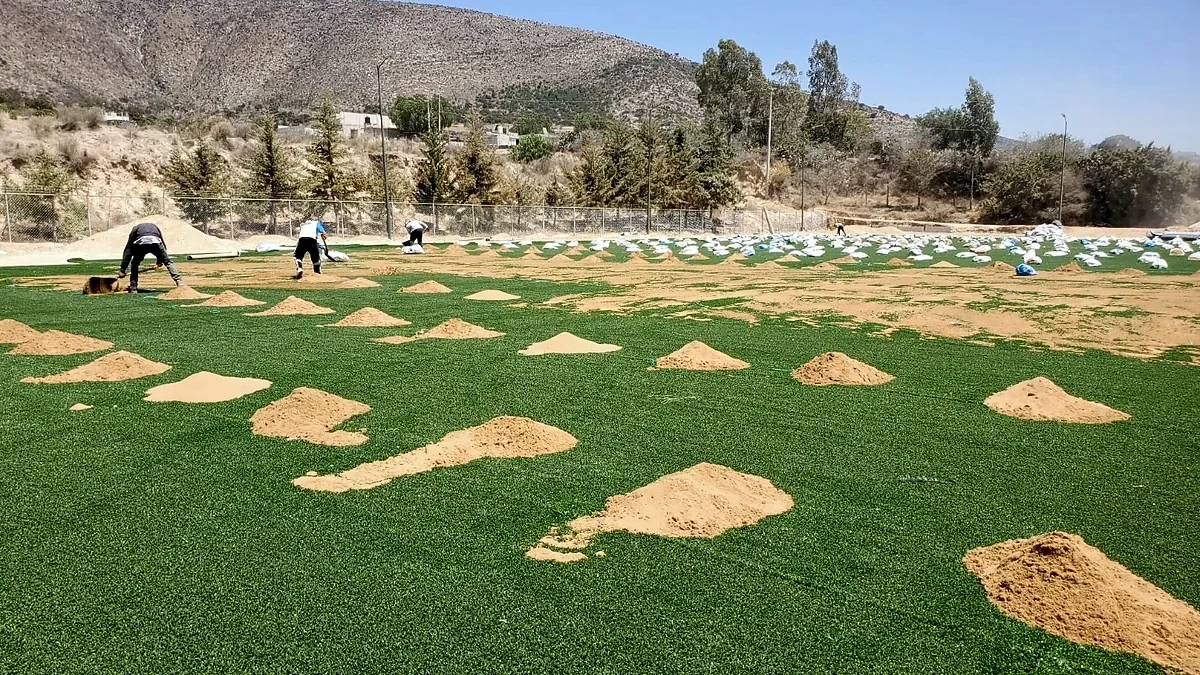 Distribución de arena sílica sobre el pasto sintético del campo de béisbol en Santiago Tenango, Puebla