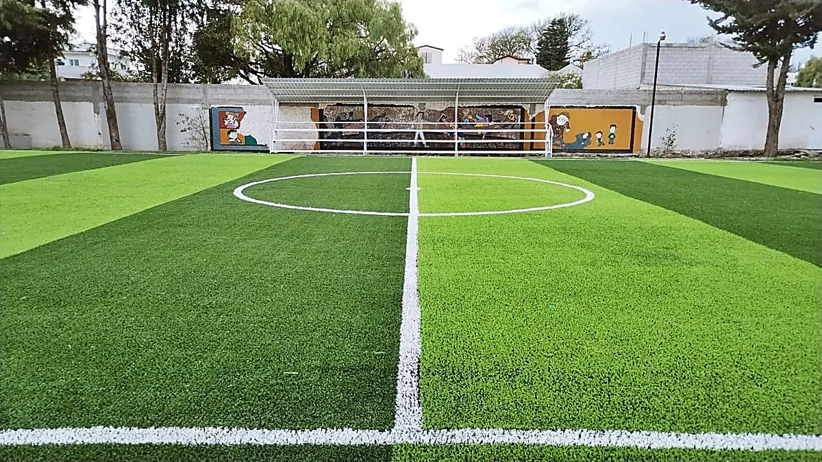 Cancha de fútbol 7 con pasto sintético en Deportivo Felipe Ángeles, Puebla: líneas de juego insertadas en el mismo pasto