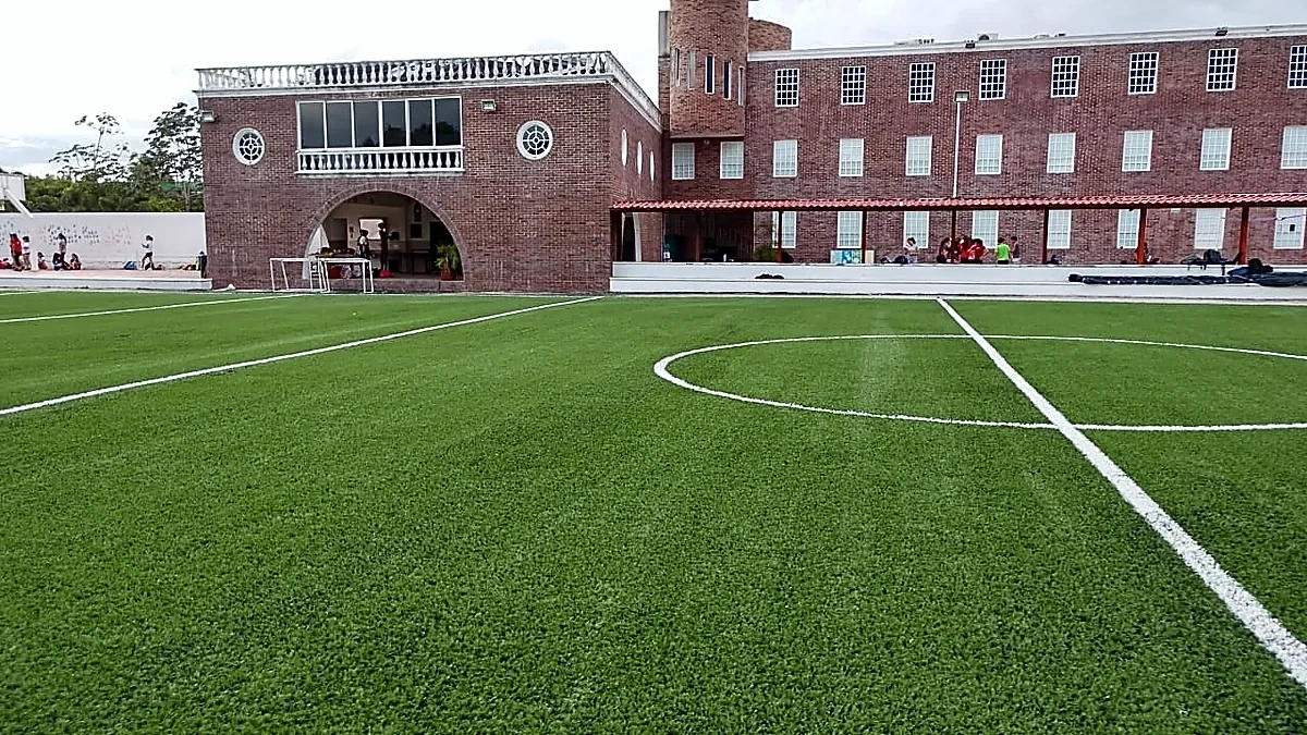 Campo de fútbol americano con pasto sintético en Colegio Álamos, Cancún, Quintana Roo: yardas y números insertados en el pasto