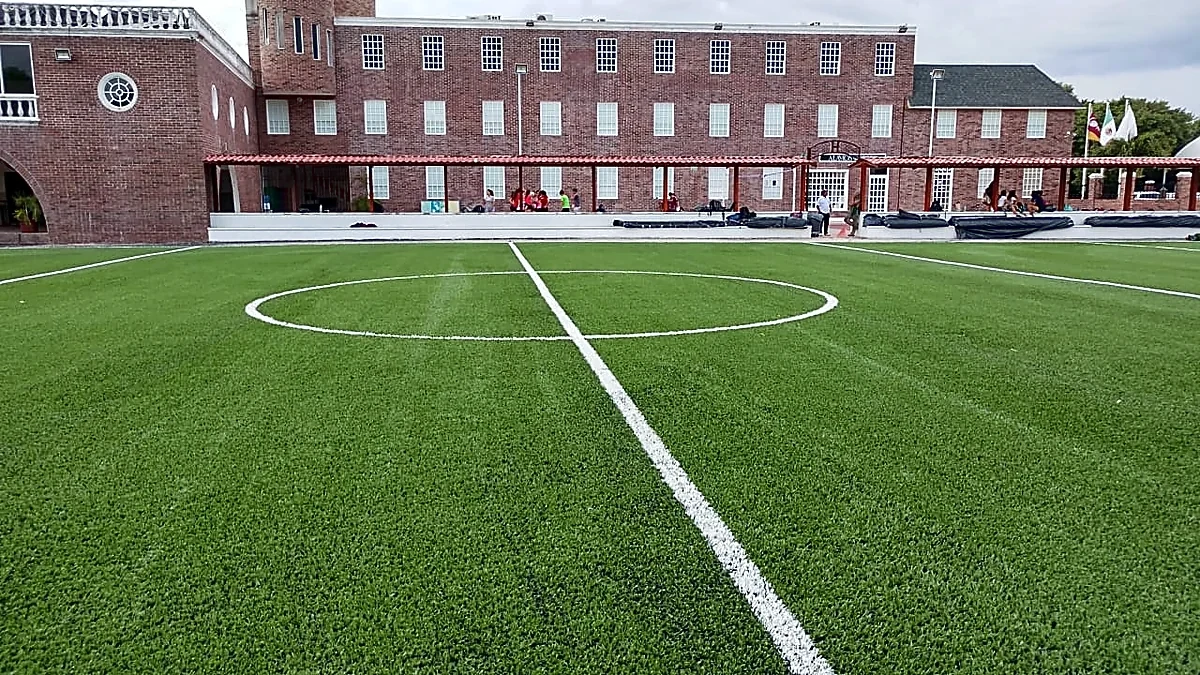 Campo de fútbol americano con pasto sintético en Colegio Álamos, Cancún, Quintana Roo: el campo desde la línea lateral