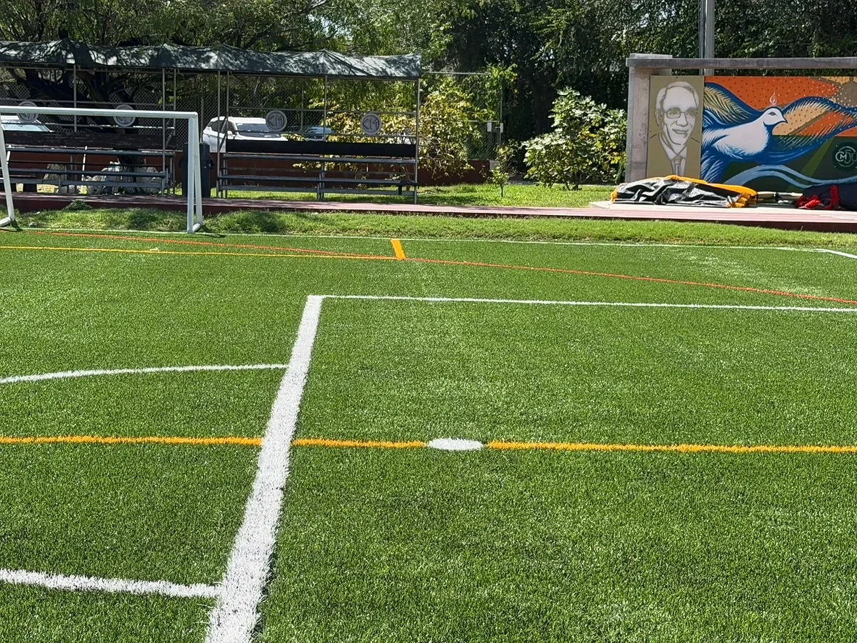 Área de portería con líneas insertadas en pasto sintético y bancas en la cancha del Colegio Mexicano, Reynosa