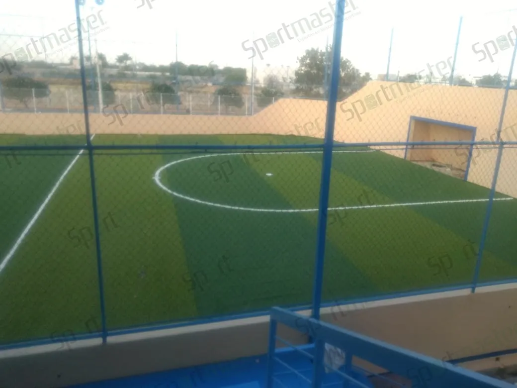 Cancha de fútbol rápido con pasto sintético en Colegio Lasaye, Ciudad Victoria, Tamaulipas: la cancha vista a través del cerco, con el círculo central
